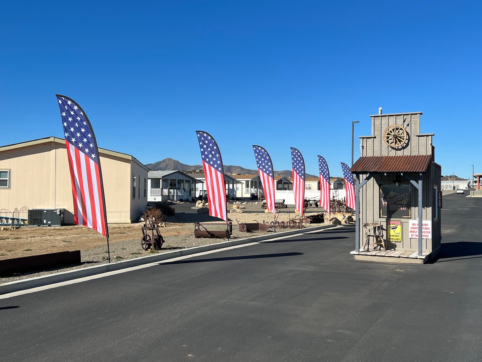 The Old West-style welcome entrance at Orchard Ranch North Resort, lined with American flags.